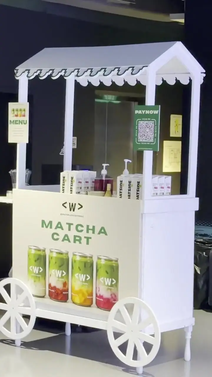 A Waterloo barista pouring a strawberry matcha beside the Waterloo matcha menu at an event