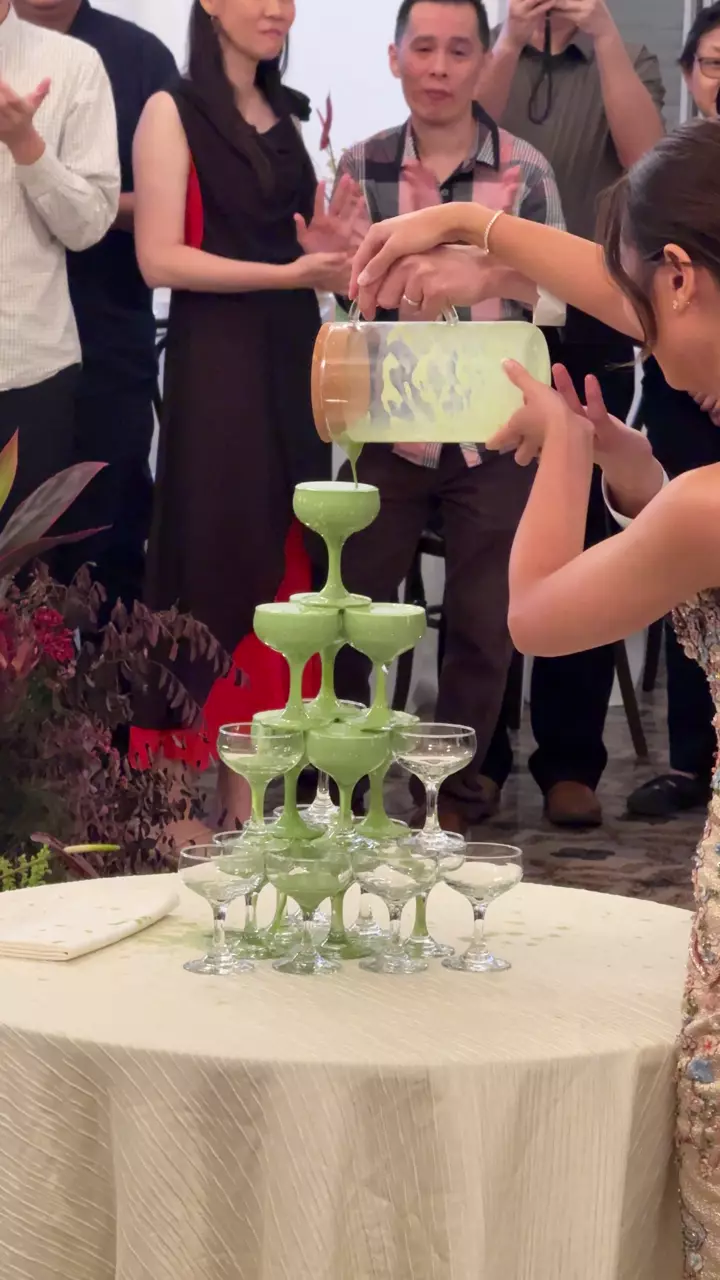 A Waterloo matcha tower being poured into a pyramid of glasses as guests look on at a celebration